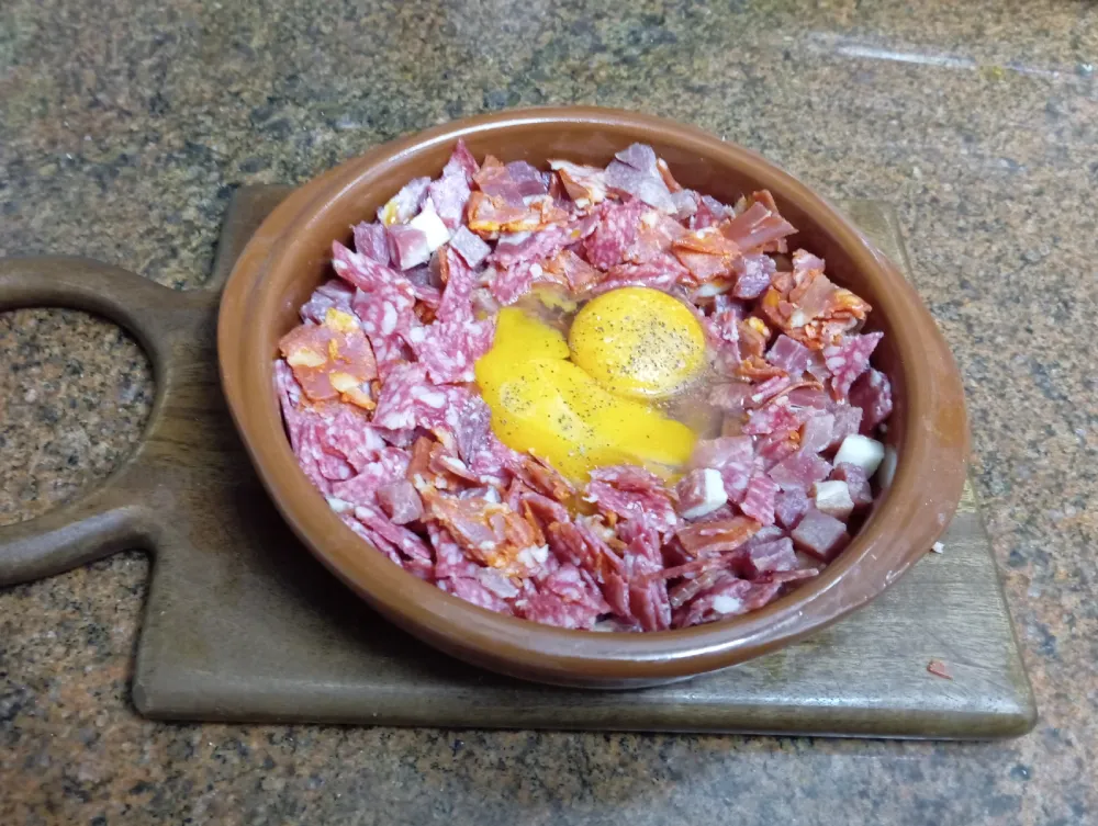 Egg on a plate with chorizo, salami and ham